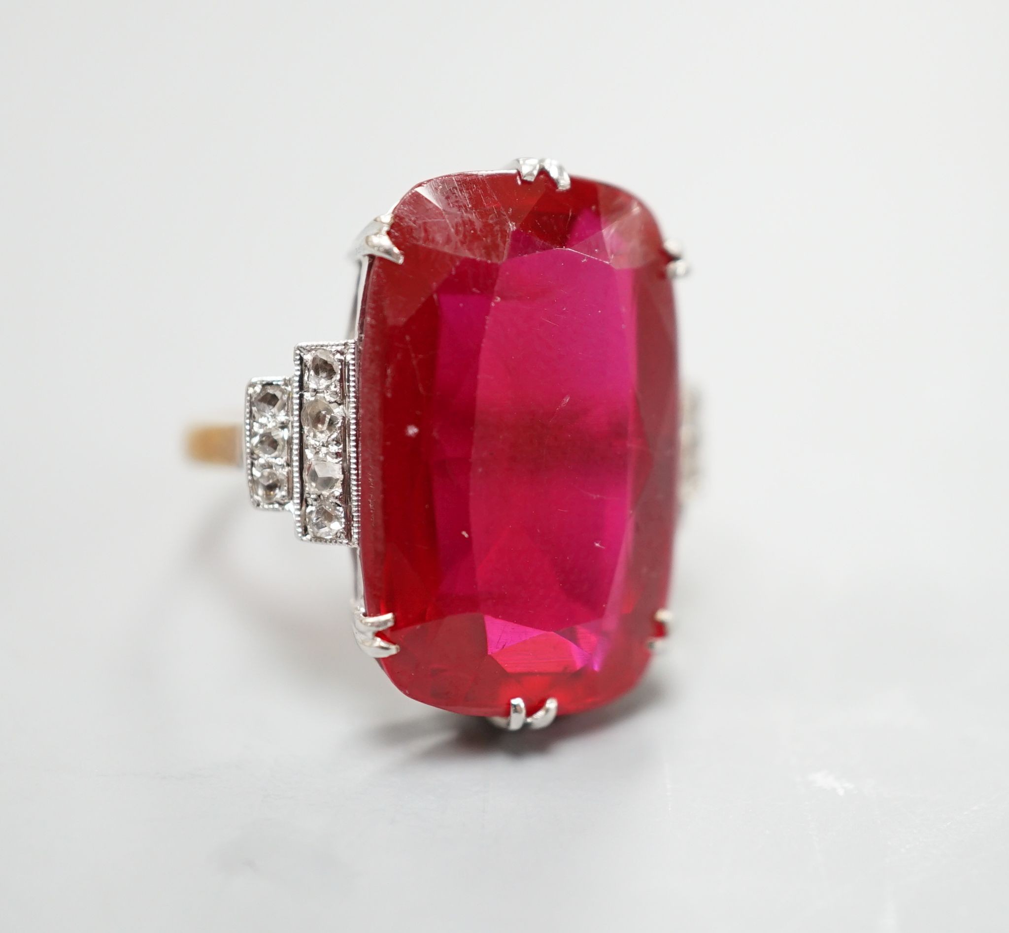 A yellow metal and large synthetic ruby set dress ring, with rose cut diamond set stepped shoulders, size L/M, gross weight 8 grams.